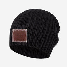 Load image into Gallery viewer, This black beanie features a red maple leather patch debossed with the Love Your Melon logo on the front. These beanies are very cozy and warm and have a slouchier fit. Details: Yarn Color: Black Sizing: 9” x 11” standard when uncuffed. One Size. Content: 99% Cotton 1% LYCRA® Care: Machine wash cold. Use mild detergent. Tumble dry on high.